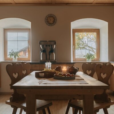 Fully equipped kitchen and dining area in the holiday apartment, featuring a wooden table, chairs, and a view of the landscape.