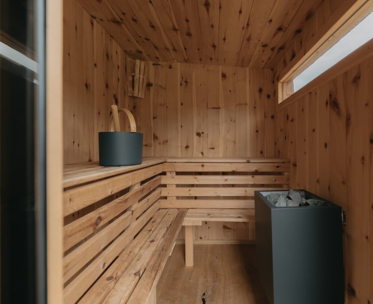 The private sauna in the holiday apartment, featuring wooden benches, a sauna heater, and accessories.