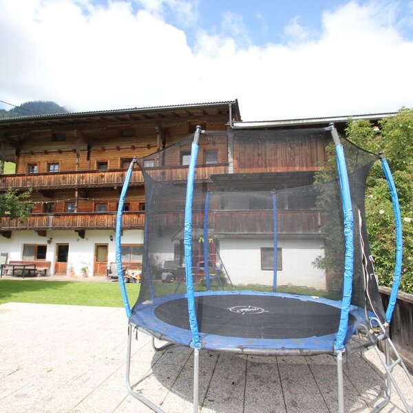 A trampoline with a safety net is available on the paved outdoor area of the Farm House.