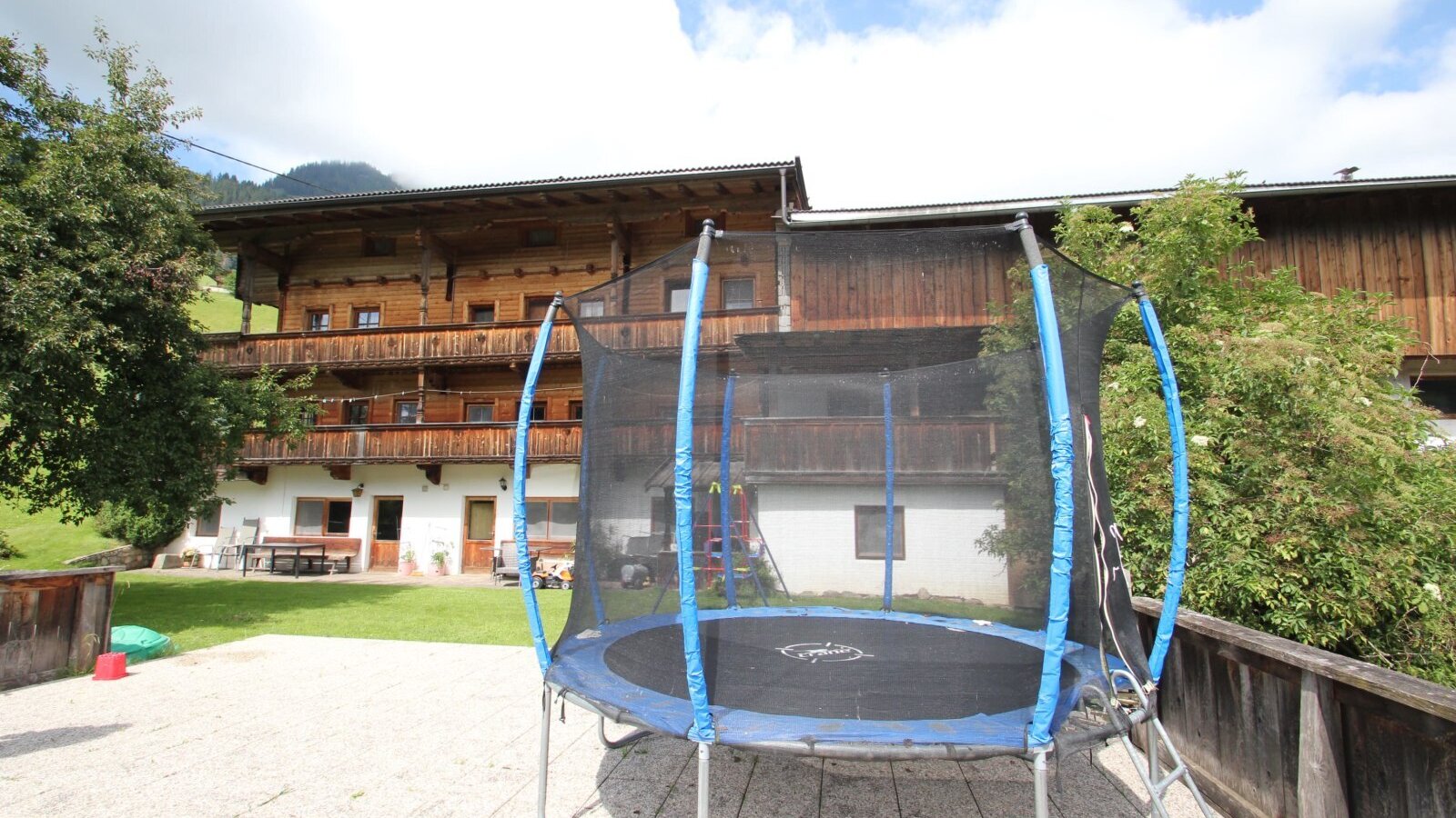 A trampoline with a safety net is available on the paved outdoor area of the Farm House.