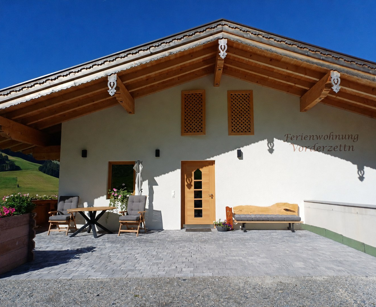 The apartment terrace with comfortable seating options under a charming wooden roof overhang.