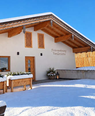 The farmhouse's inviting, snow-covered entrance area under a bright, clear blue sky.