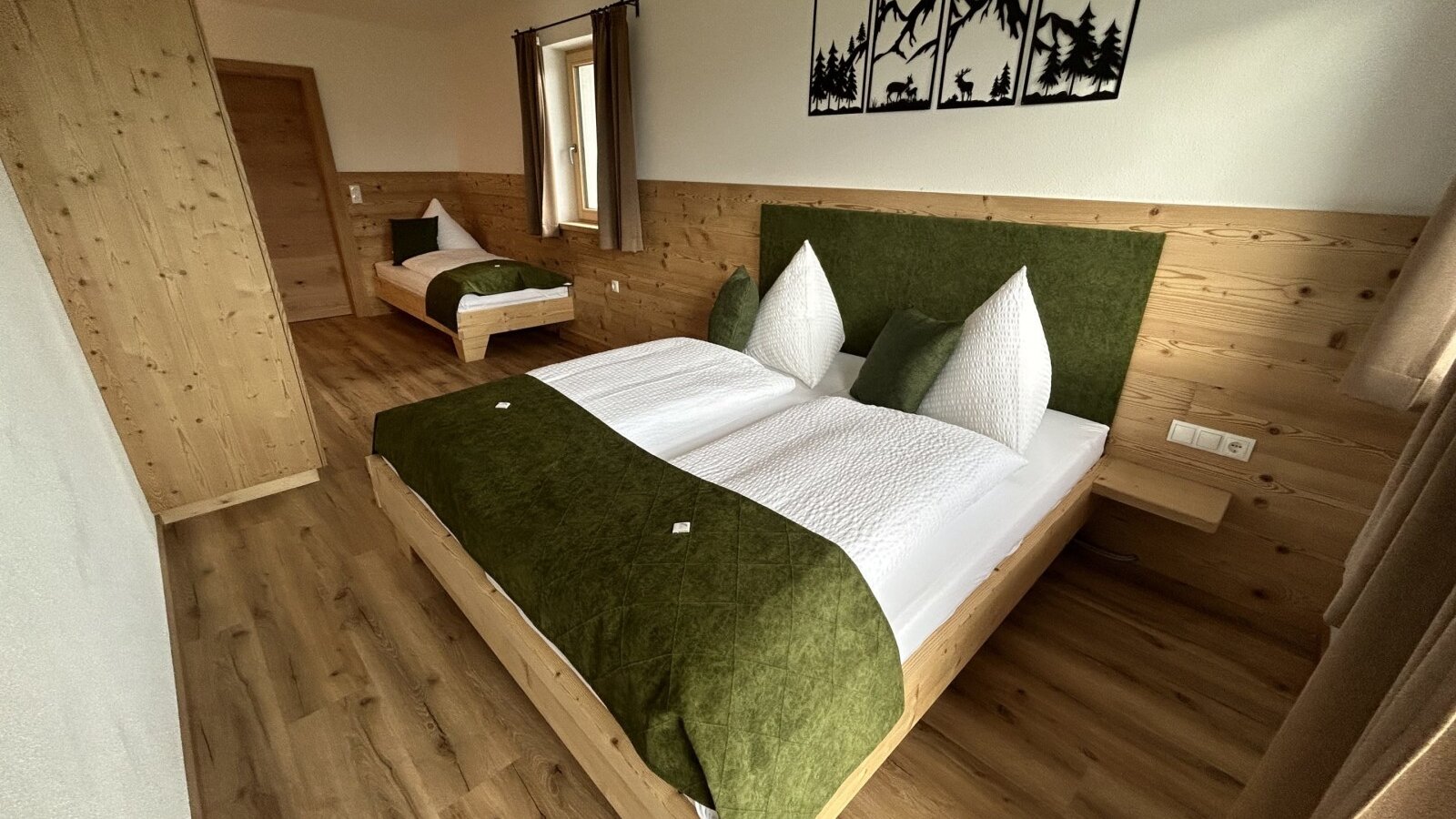 Bedroom in the farm house with a double bed, a single bed, a wooden wardrobe, and wooden wall paneling.