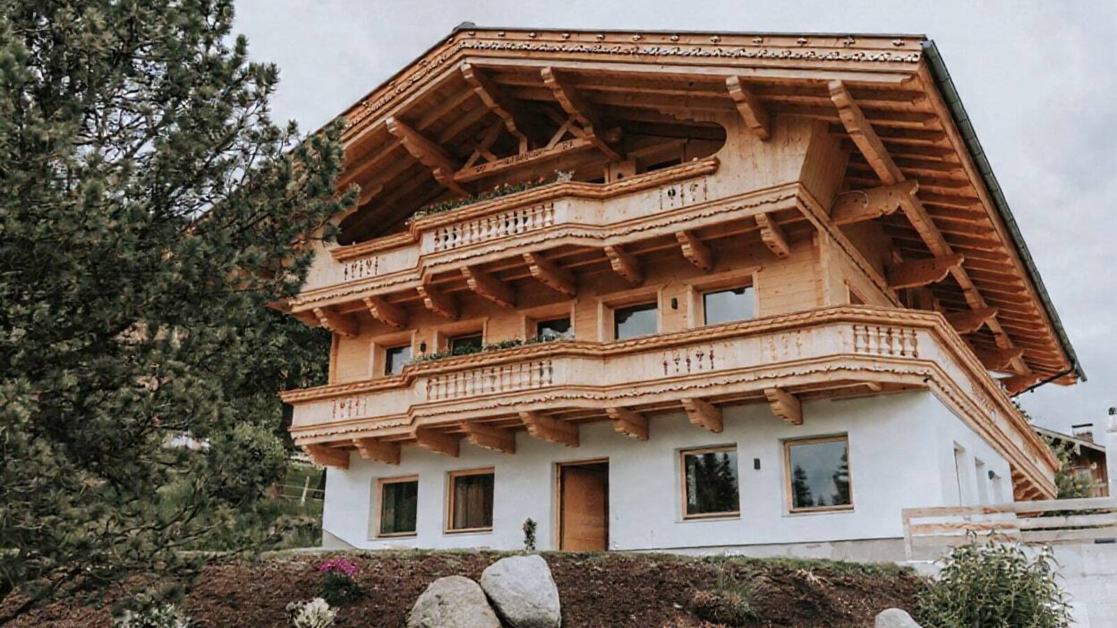 Exterior view of the farmhouse with multiple floors, wooden balconies, and a white facade.
