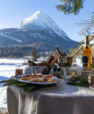 An inviting outdoor table at the apartment with delicious snacks set against a scenic, snow-covered mountain backdrop.