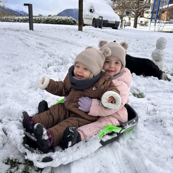 Two children enjoy sledding in the snow at the Farm House, highlighting outdoor winter activities.