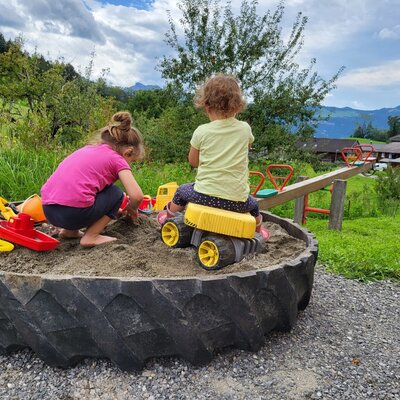 The farmhouse's play area featuring a sandbox and a seesaw for children.