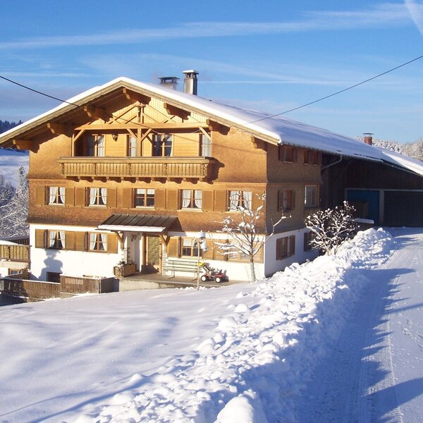 The Farm House exterior in a snowy mountain landscape, featuring traditional wooden architecture and balconies.
