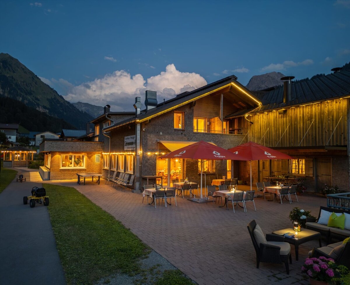 The farmhouse's inviting terrace in the evening, featuring cozy seating areas and warm, atmospheric lighting.