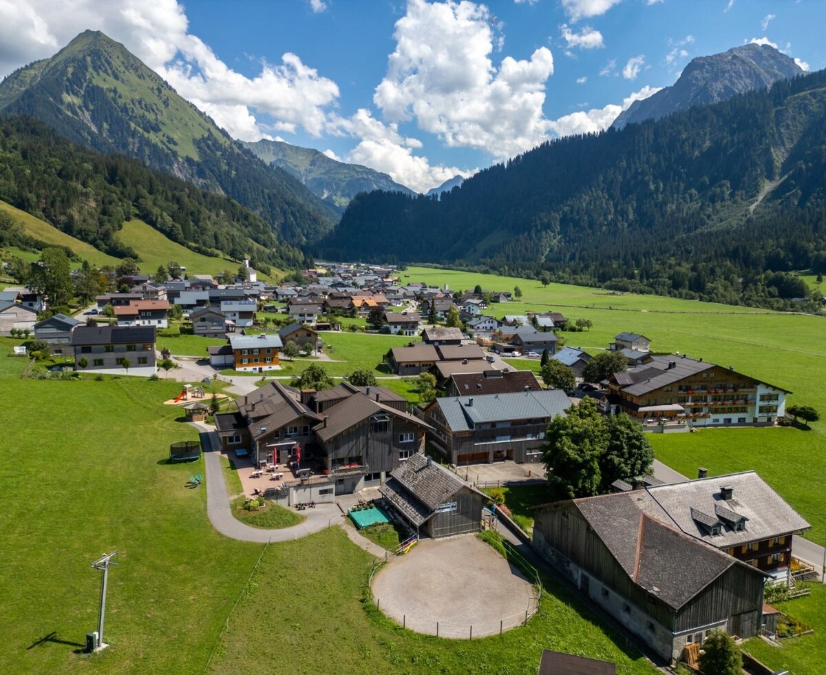 The inviting Bauernhof nestled in a lush green valley, surrounded by a scenic mountain landscape.