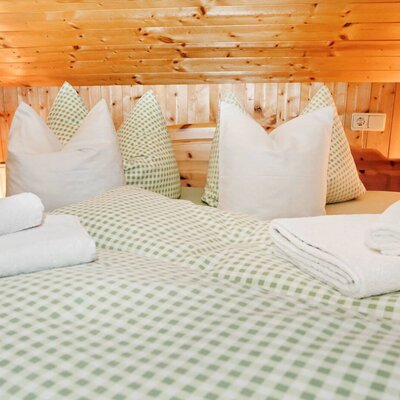 The bedroom of our holiday flat is furnished with light-coloured wood and a rustic pitched roof.