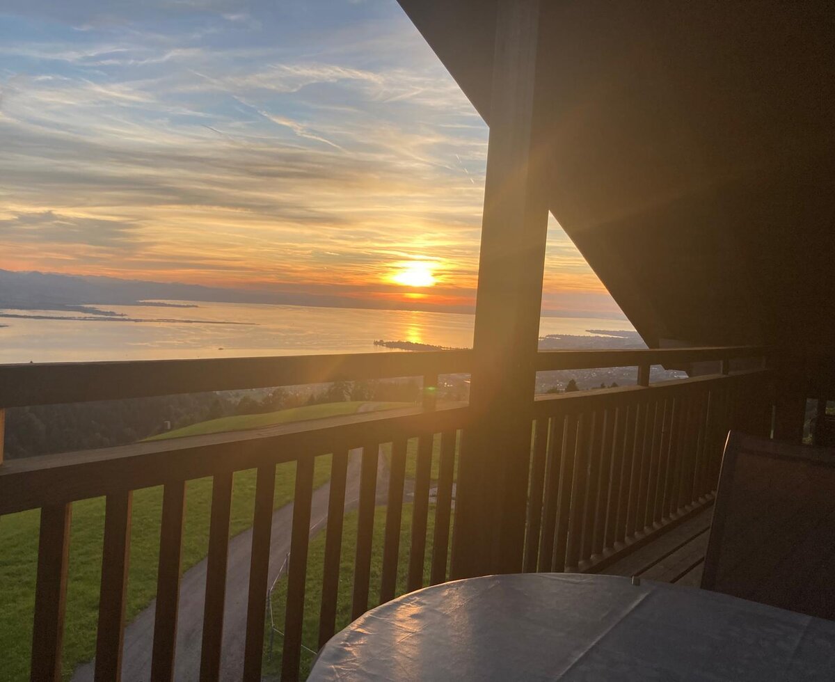 An atmospheric sunset view over the lake from the farmhouse's wooden balcony.