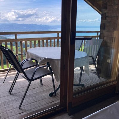 The farmhouse's inviting balcony with a cozy seating area and a scenic view of the lake and surrounding hills.