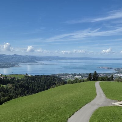 Expansive view from the farmhouse of the shimmering lake and the surrounding green hills.