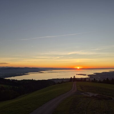 Scenic sunset view from the farmhouse overlooking the shimmering lake and surrounding mountains.