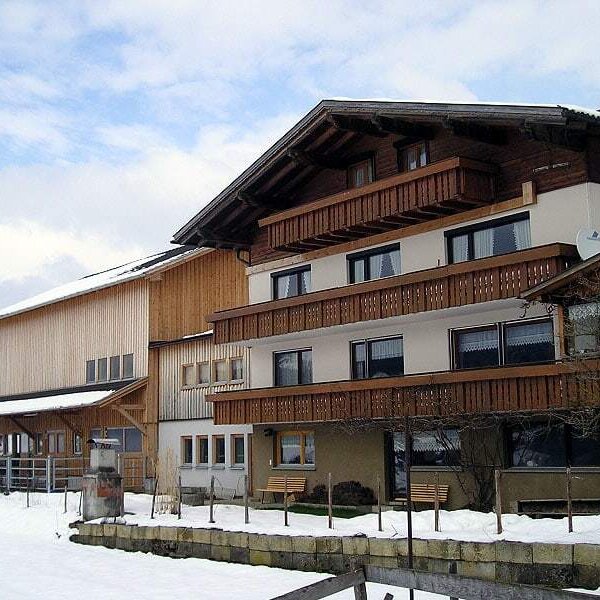 The exterior of the Farm House, featuring multiple balconies and natural wooden siding, surrounded by snow. The exterior of the Farm House, featuring multiple balconies and natural wooden siding, surrounded by snow.