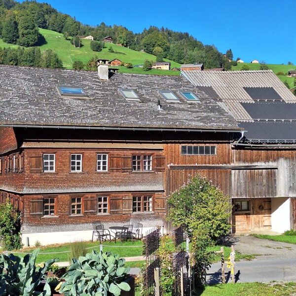 Our farmhouse with a charming wooden facade, surrounded by lush green hills.
