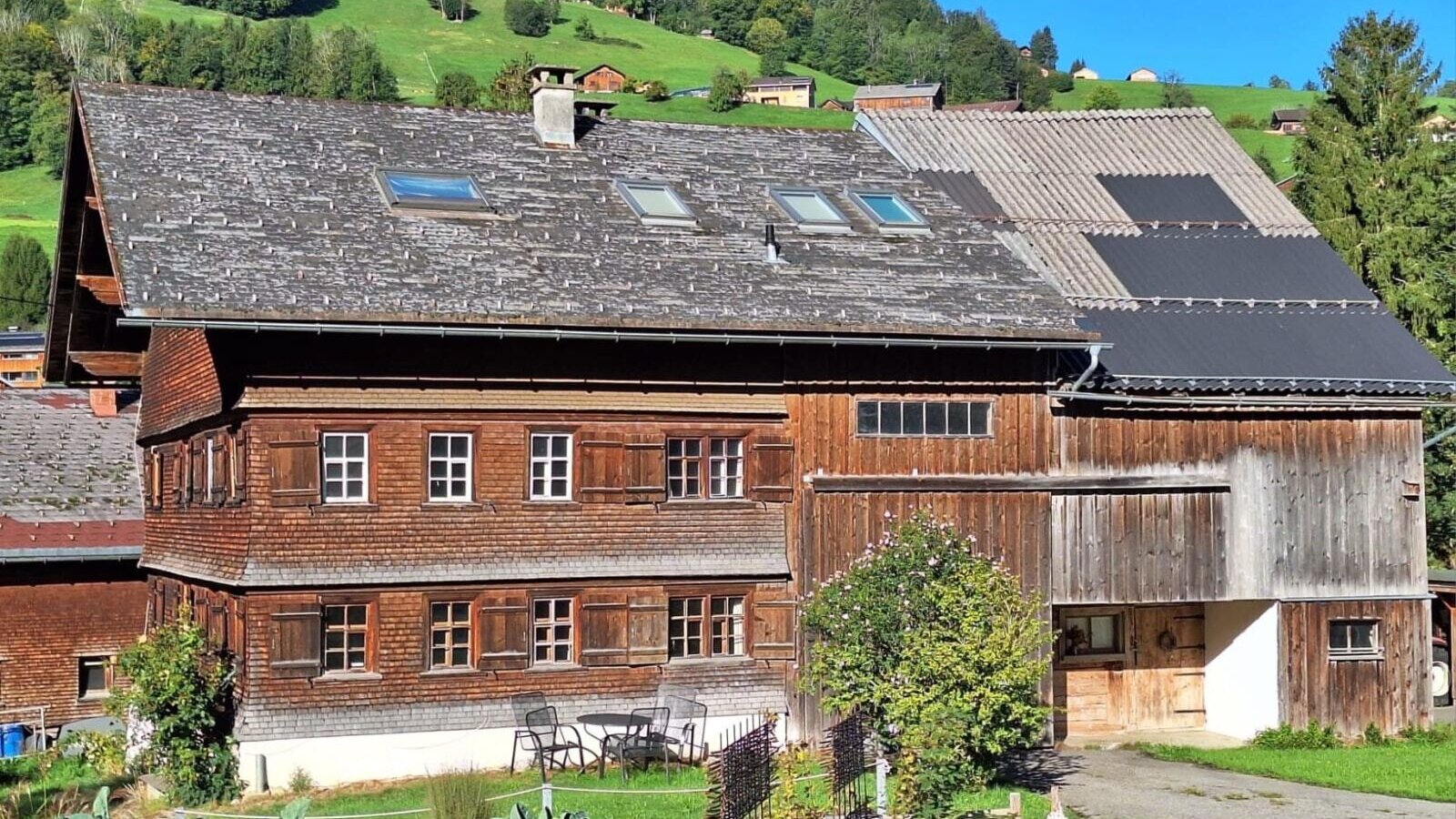 Our farmhouse with a charming wooden facade, surrounded by lush green hills.