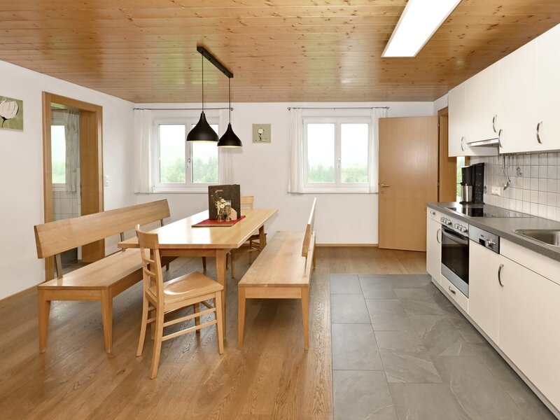 The living kitchen of the apartment at the farmhouse, featuring a dining table with benches and a fully equipped kitchen including a dishwasher and oven.