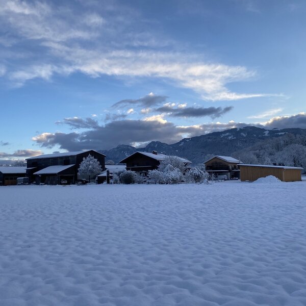 The Farm House buildings and snow-covered fields with distant snow-capped mountains under a winter sky.