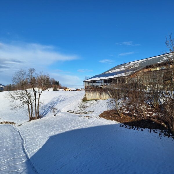 Our home - surrounded by snow-covered fields and mountains on a sunny winter day.