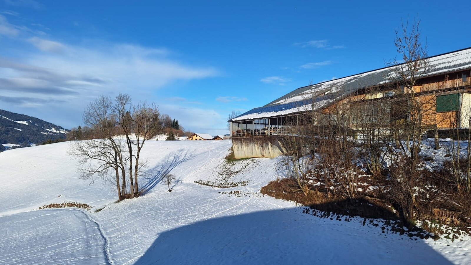 Our home - surrounded by snow-covered fields and mountains on a sunny winter day.
