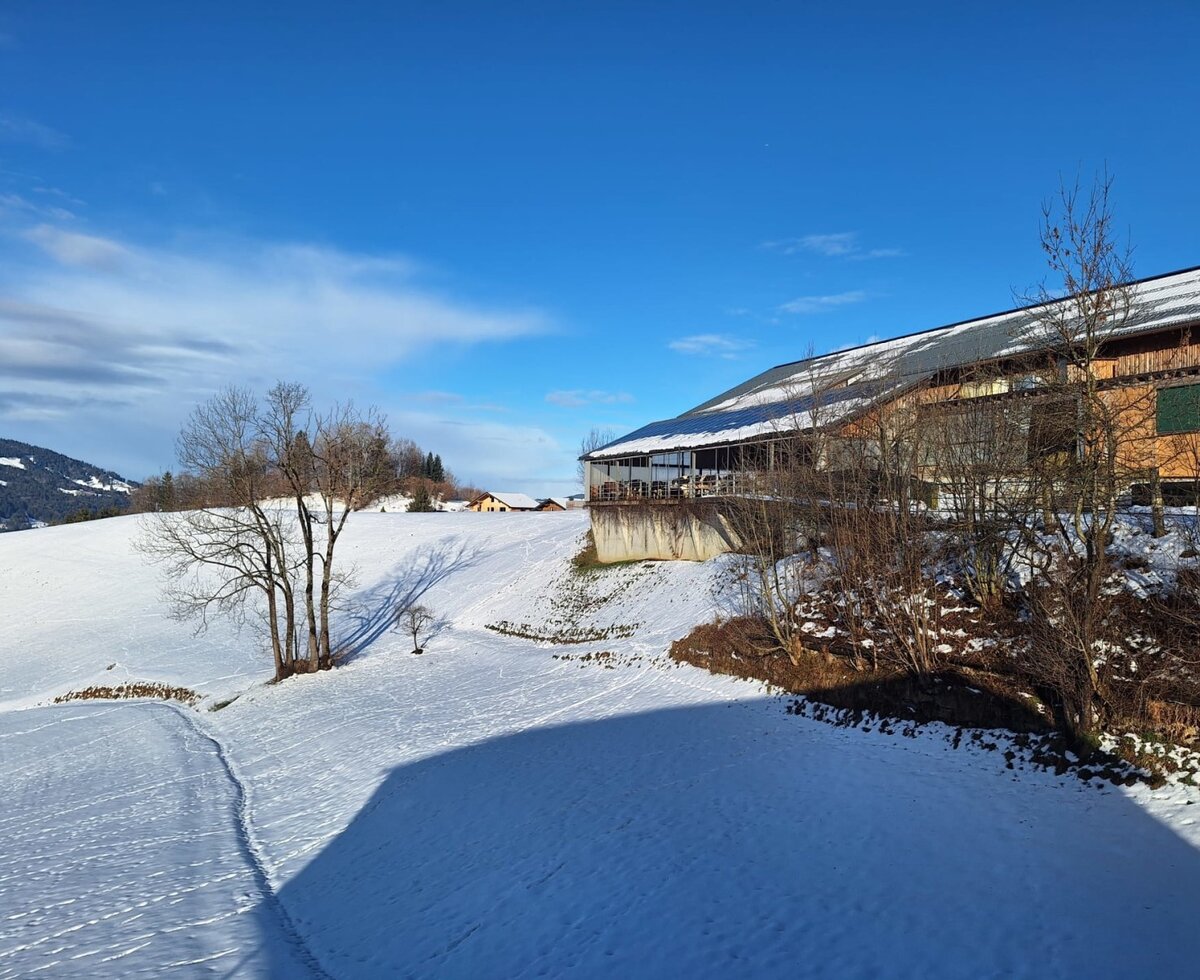 Our home - surrounded by snow-covered fields and mountains on a sunny winter day.