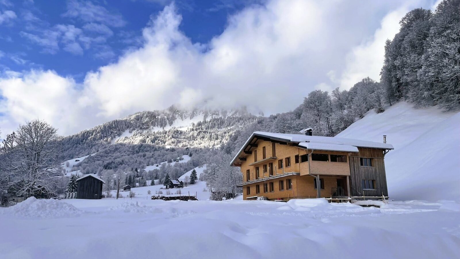 The house with a wooden facade and balconies, set in a snowy mountain landscape.