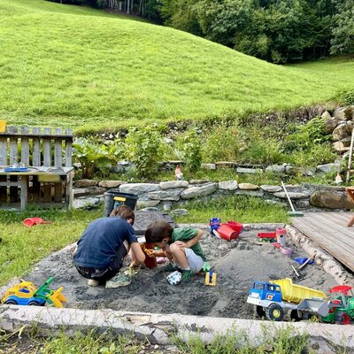 The apartment's inviting garden features a spacious sandbox with toys.