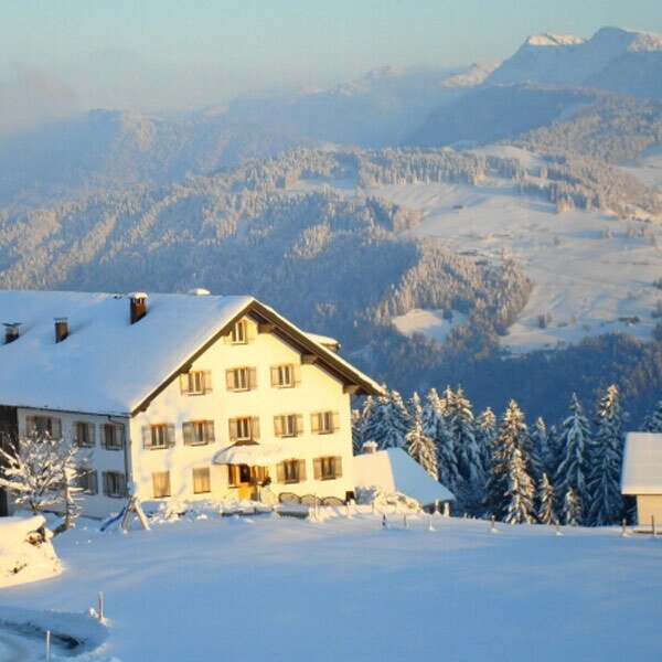 The Farm House exterior in a snowy winter landscape, with surrounding trees and mountains. The Farm House exterior in a snowy winter landscape, with surrounding trees and mountains.
