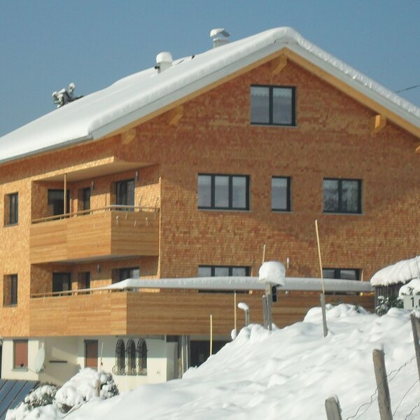 The farm house exterior featuring a wooden facade, snow-covered roof, and private guest balconies.