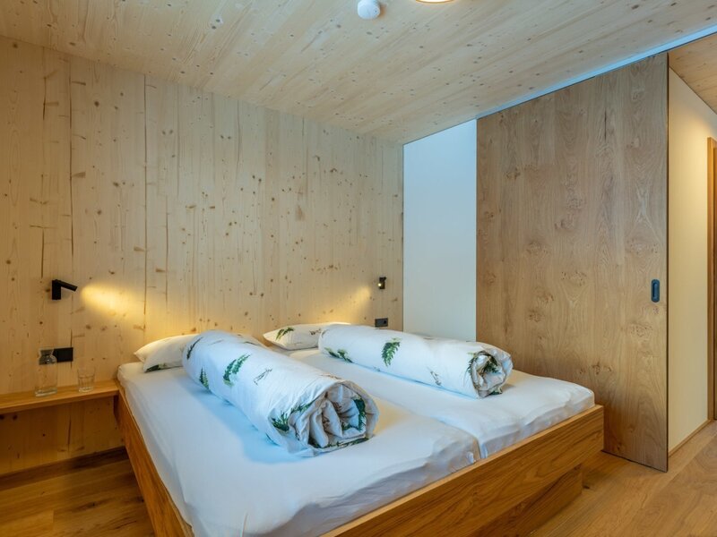 A cozy bedroom in the bed and breakfast featuring natural wood paneling, warm bedside lighting, and an inviting double bed.