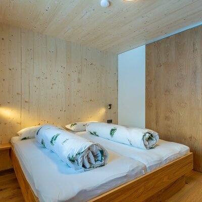 A cozy bedroom in the bed and breakfast featuring natural wood paneling, warm bedside lighting, and an inviting double bed.