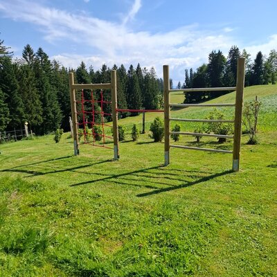 Children's playground at the farmhouse with a climbing net and monkey bars.
