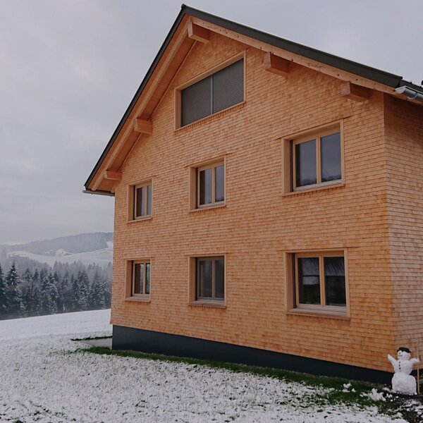 The exterior of the newly built Farm House, featuring a light wooden facade, multiple windows, and a snow-covered landscape with evergreen trees. The exterior of the newly built Farm House, featuring a light wooden facade, multiple windows, and a snow-covered landscape with evergreen trees.