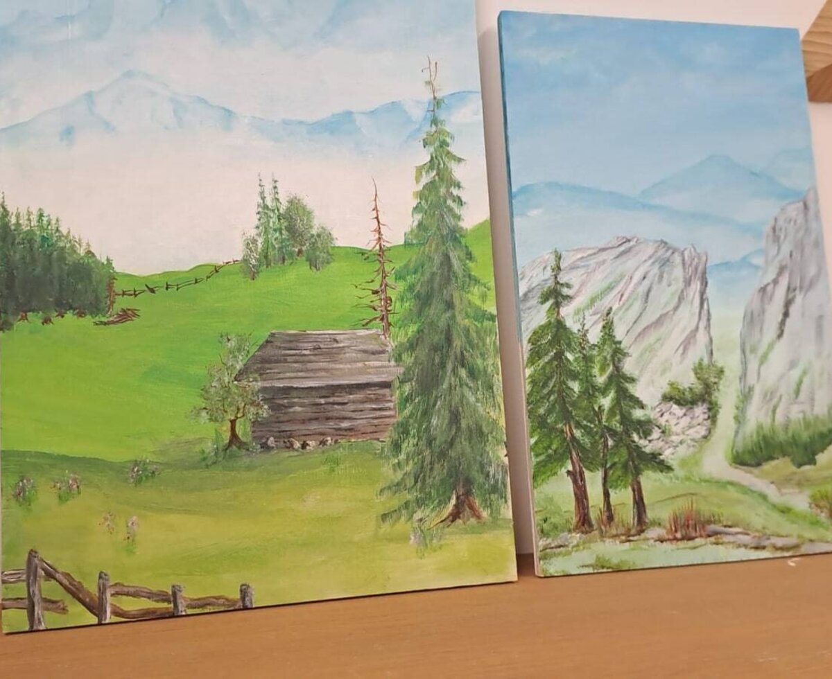 Paintings of mountain landscapes featuring a wooden hut and trees as decoration in the farmhouse.
