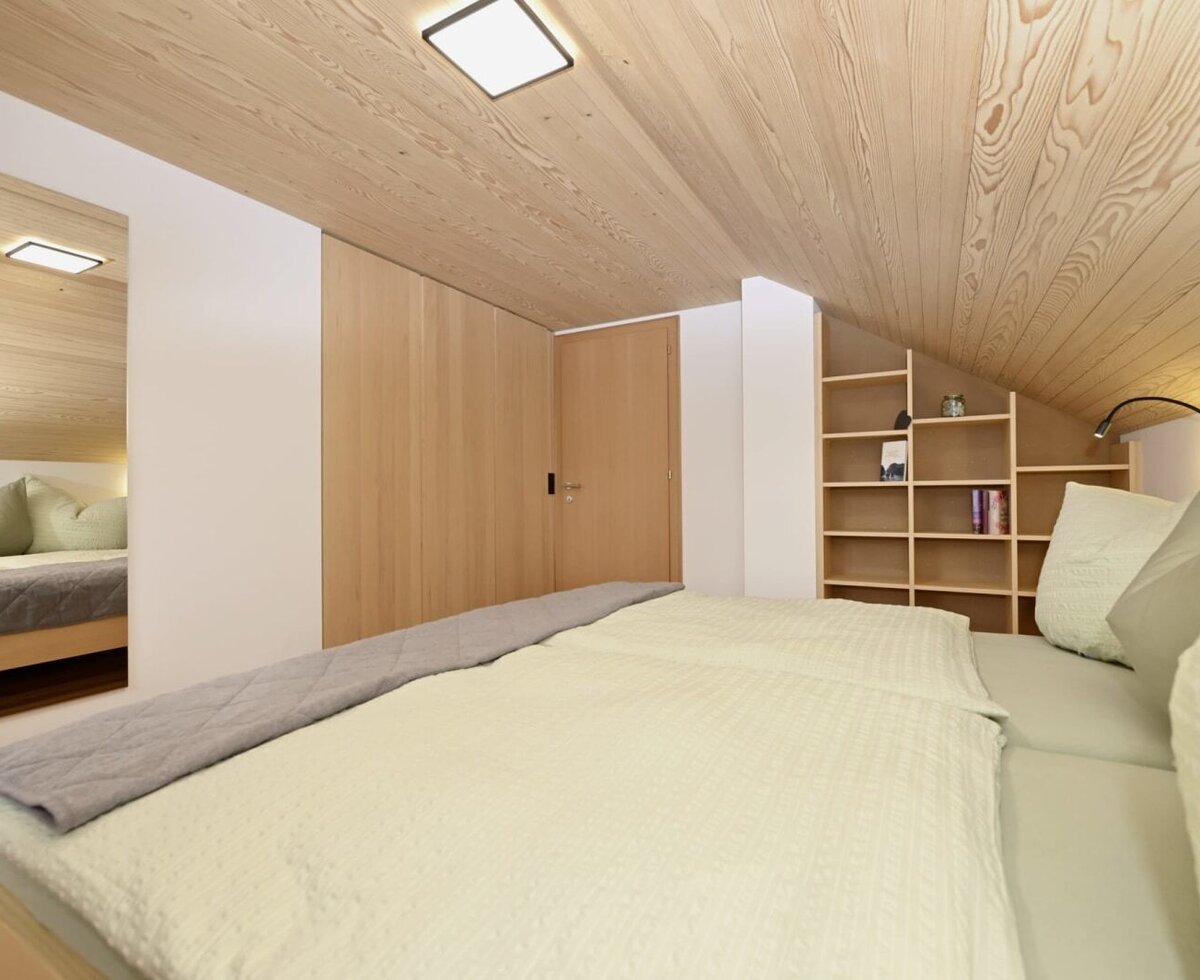 Bedroom in the farmhouse with a large bed, wooden ceiling, built-in wardrobes, and shelving.