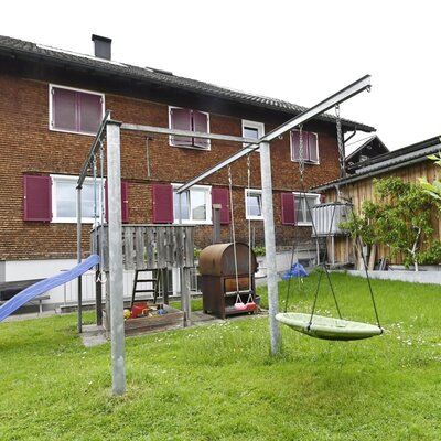 Children's playground in the garden of the farmhouse, featuring a slide, swings, and a sandbox.