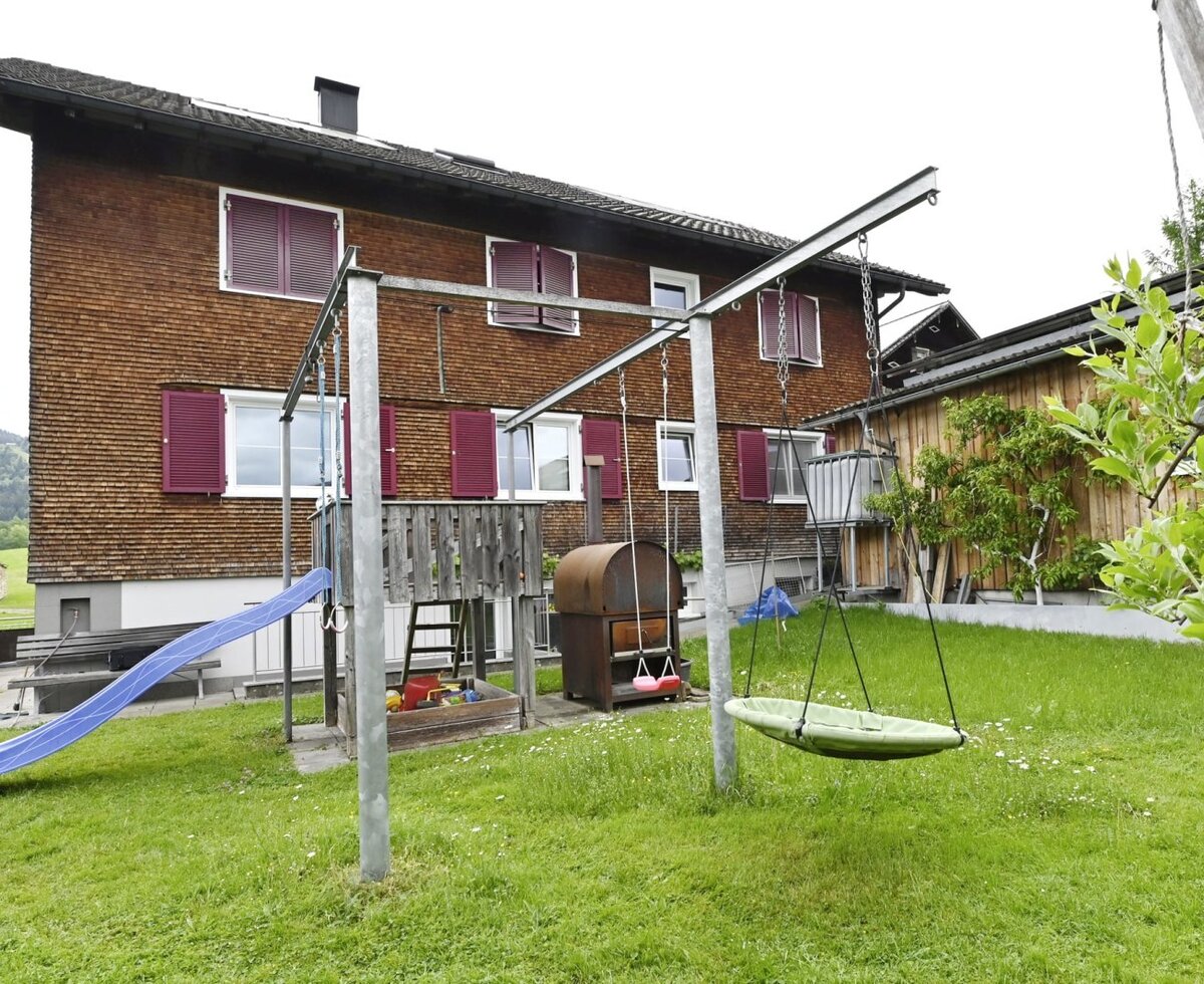 Children's playground in the garden of the farmhouse, featuring a slide, swings, and a sandbox.