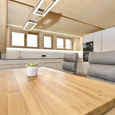 Dining area and kitchen in the farmhouse with a large wooden table, comfortable chairs, and modern built-in appliances.