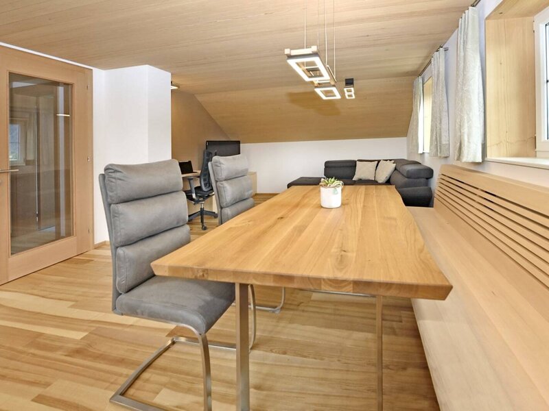 The farmhouse dining area features a wooden table, chairs, and a built-in bench, adjacent to the living area with a sofa.