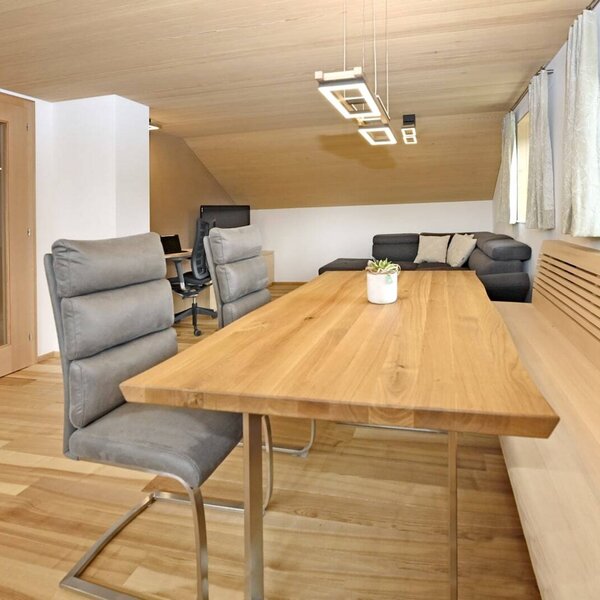 The farmhouse dining area features a wooden table, chairs, and a built-in bench, adjacent to the living area with a sofa.
