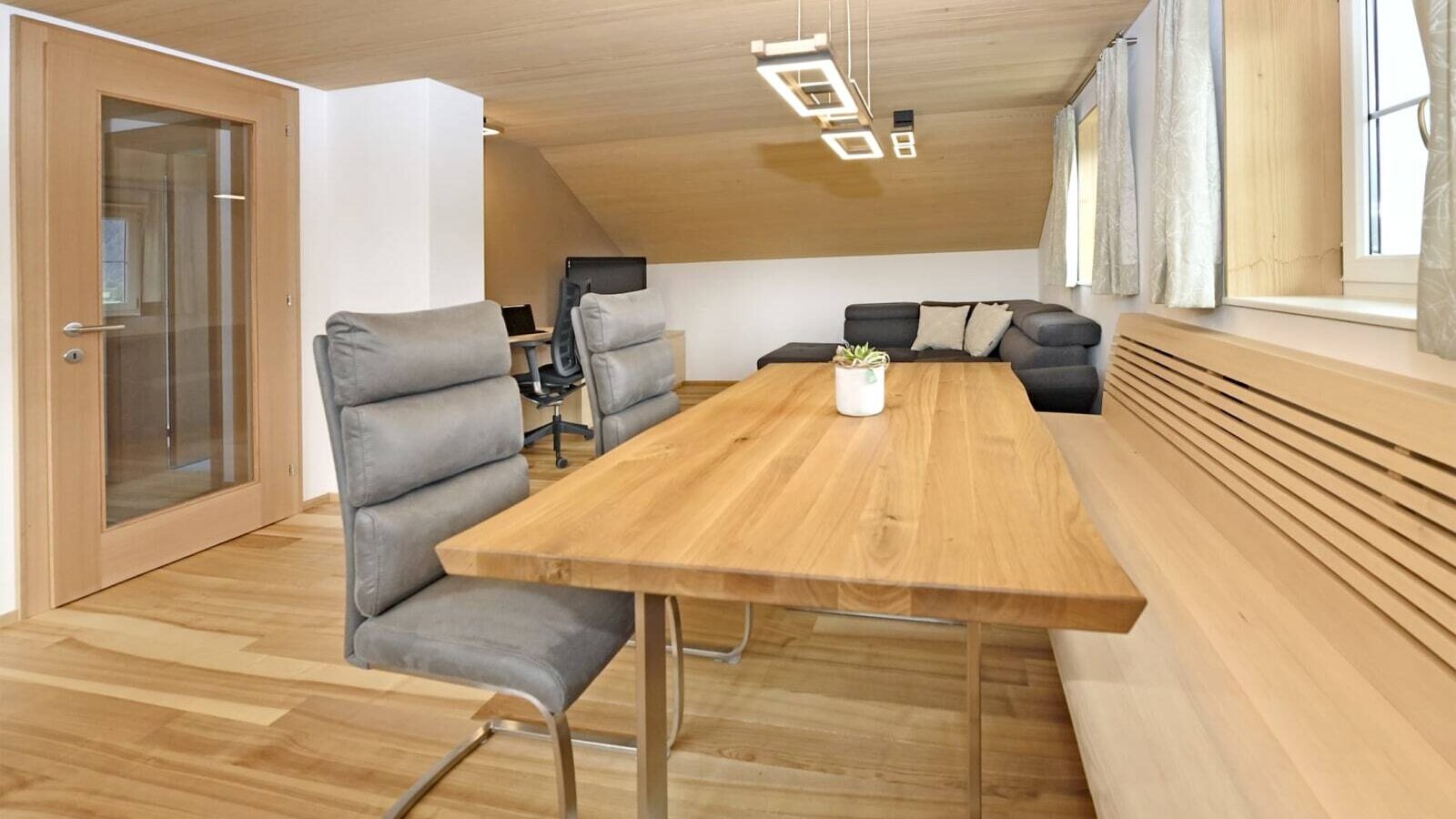 The farmhouse dining area features a wooden table, chairs, and a built-in bench, adjacent to the living area with a sofa.