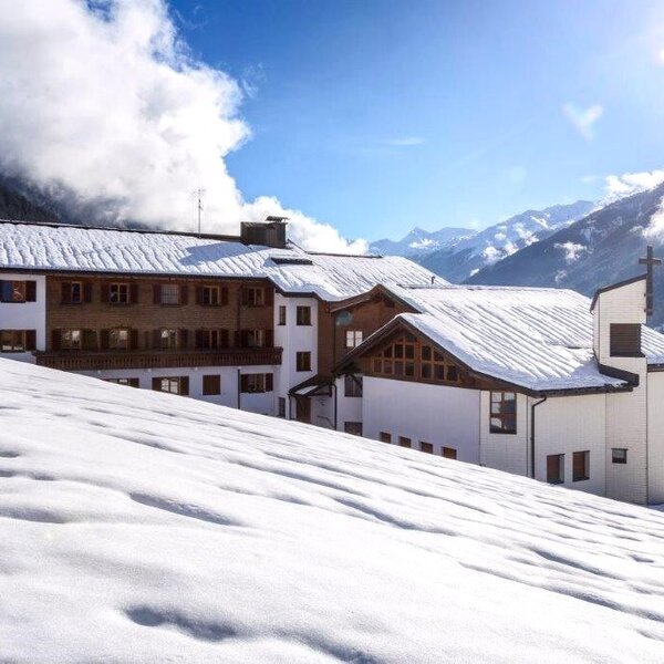 The multi-story Farm House with snow-covered roofs, located in a winter mountain landscape and featuring an attached chapel. The multi-story Farm House with snow-covered roofs, located in a winter mountain landscape and featuring an attached chapel.