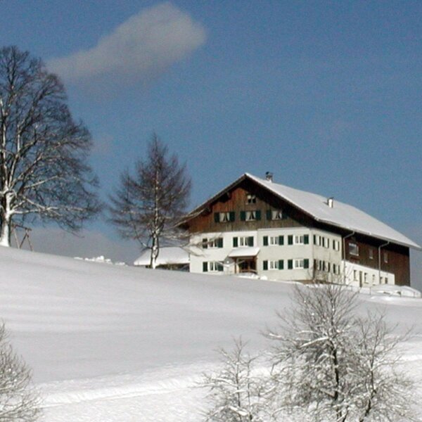 The Farm House exterior, with its white and wooden facade and snow-covered roof, surrounded by a winter landscape. The Farm House exterior, with its white and wooden facade and snow-covered roof, surrounded by a winter landscape.
