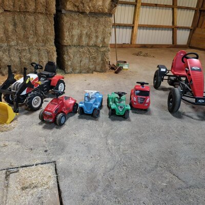 Children's vehicles including a tractor, bobby cars, and a pedal go-kart for young guests at the farmhouse.