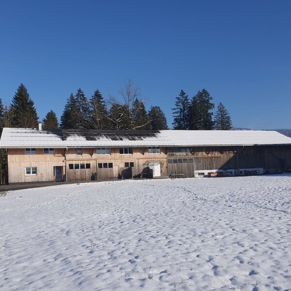The exterior of the Farm House, featuring a wooden facade and snow-covered roof and grounds during winter.
