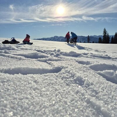 A family enjoys a winter hike in the snow with mountain views from the Bauernhof.